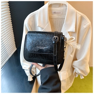 Détail du mini sac noir en cuir verni plissé avec perles et boucle dorée élégante