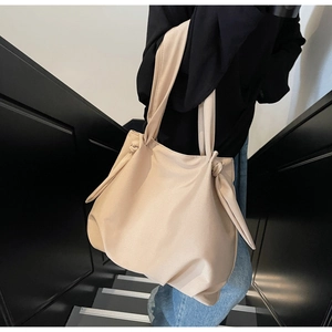 Detail of minimalist beige tote bag with stylish knot handle on matte fabric surface
