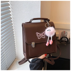 Détail du sac à dos marron foncé en similicuir avec broderie papillon et boucle métallique