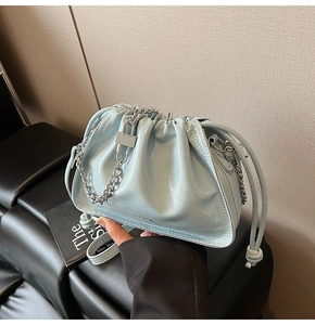 Detail of light blue patent leather bucket bag with silver chain and drawstring closure