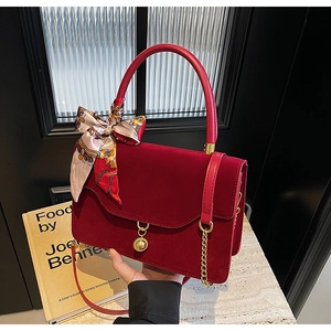 Detail of red suede bridal bag with printed silk scarf and golden chain strap