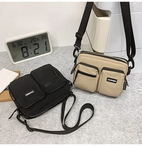Detail of multi-pocket canvas crossbody bags in black and beige with adjustable straps