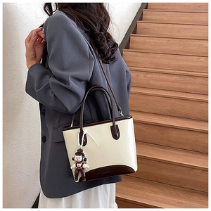 Détail du sac seau bicolore avec pendentif perle et texture en cuir lisse brillant