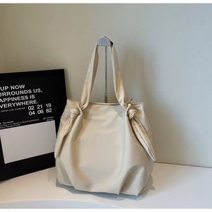 Detail of cream canvas tote bag featuring decorative knot shoulder strap accents