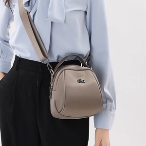 Detail of khaki crossbody shell bag with adjustable wide strap and circular metal logo