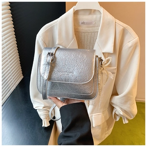 Détail du sac à bandoulière argenté avec texture plissée et nœud en perles et dentelle