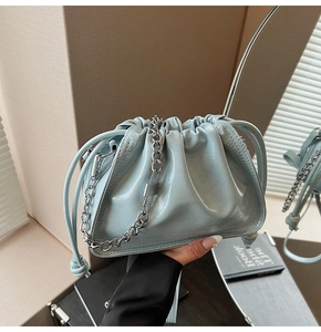Detail of light blue glossy drawstring bucket bag with silver chain and lock charm