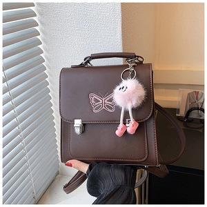 Détail du sac à dos marron avec broderie papillon violette et pendentif pompon doux