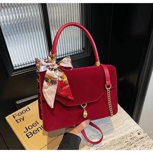 Detail of red velvet handbag featuring a silk scarf wrap and golden hardware