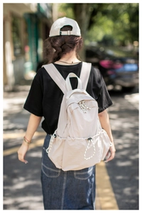 Outdoor shot showing back view of cream nylon backpack with adjustable wide straps