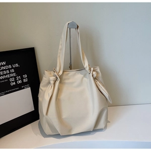 Detail of minimalist cream canvas tote bag with decorative knot on shoulder strap