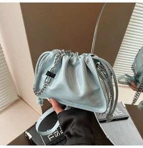 Detail of light blue pleated bucket bag with silver chain and brand logo on bottom