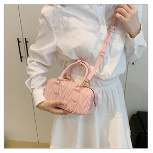 Detail of pink matelassé quilted mini crossbody bag with gold hardware and shoulder strap