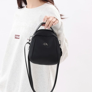 Close-up of black shell-shaped crossbody bag with silver logo and adjustable strap