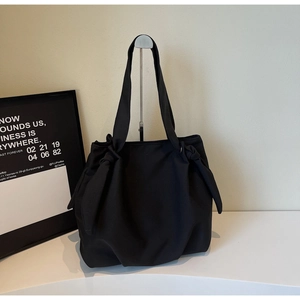 Detail of minimalist black tote bag featuring unique knotted handle and heavy canvas texture