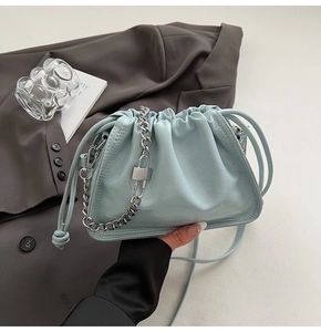 Detail of light blue pleated cloud bag with silver chain strap and metal lock