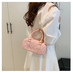 Detail of pink quilted leather cylinder bag worn crossbody with elegant white dress
