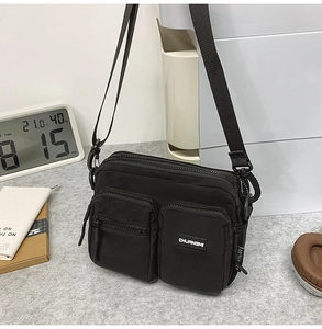 Detail view of black nylon crossbody bag with multi-pocket design and adjustable strap