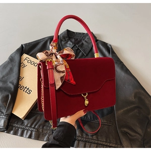 Detail of dark red velvet handbag with silk scarf decor and gold handle accessories