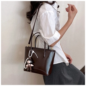 Détail du sac cabas marron foncé avec pendentif en perles et bandoulière réglable