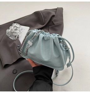 Detail of light blue pleated cloud bucket bag with silver chain handle on grey suit
