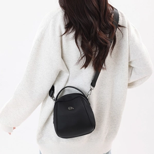 Detail of a black mini crossbody shell bag with a silver logo and adjustable strap