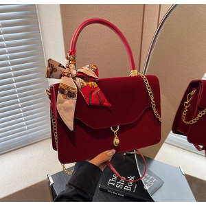 Detail of red velvet bridal handbag with gold coin pendant and floral silk scarf accessory
