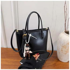 Détail du cabas en cuir noir avec breloque dessin animé et accessoires dorés en métal