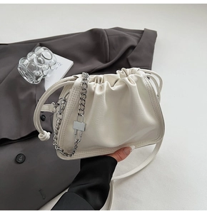 Close-up of white dumpling bag with silver chain and pleated faux leather detail