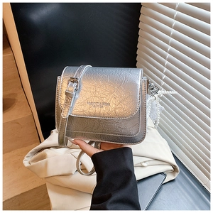 Détail du sac bandoulière argenté avec texture plissée et élégant charm fleur de perle