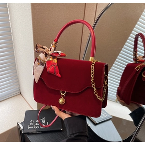 Detail of red velvet bridal handbag with golden chain and decorative silk scarf wrap