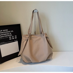 Detail of minimalist beige tote bag showing knot handle design and smooth nylon fabric