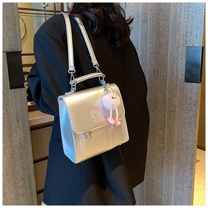 Détail du sac bandoulière argenté avec broderie papillon rose et breloque peluche