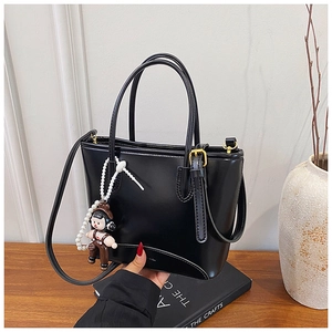 Détail du sac cabas en cuir noir brillant avec pendentif ours perlé sur bureau en bois