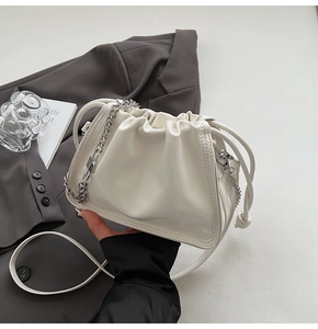 Detail of white pleated cloud bag with chunky silver chain and slim leather strap
