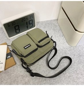 Detail of olive green nylon crossbody bag with adjustable strap and brand logo