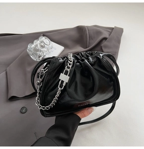Detail of black glossy pleated bucket bag with silver metal chain and lock pendant decoration