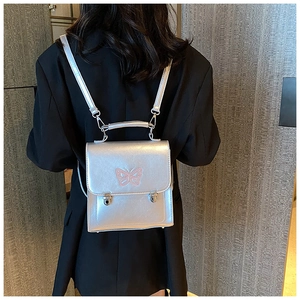 Détail du mini sac à dos argenté métallisé avec broderie papillon rose et fermoir