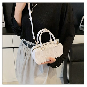 Detail of white quilted Boston bag with gold hardware and removable shoulder strap