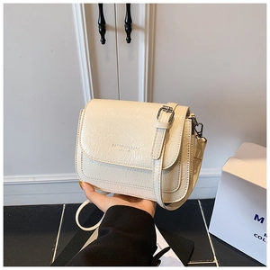 Détail du sac bandoulière crème avec texture plissée naturelle et finitions argentées