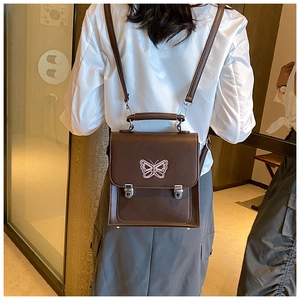 Détail d'un sac à dos vintage en cuir marron avec broderie papillon et boucles argentées