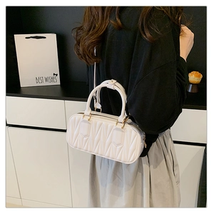 Detail of white quilted pleat handbag with gold hardware and versatile crossbody strap