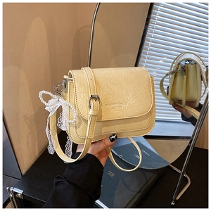 Détail du sac bandoulière crème avec texture froissée et breloque décorative en perles