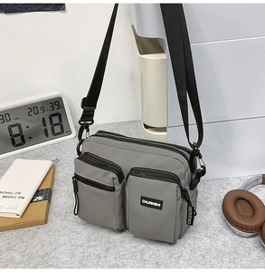Detailed view of grey multi-pocket canvas crossbody bag with durable nylon straps and zippers