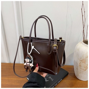 Détail du sac seau marron foncé en similicuir avec finition lisse et logo de marque doré
