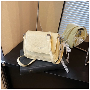 Détail du sac carré en cuir crème avec chaîne en perles et nœud sur un livre