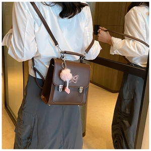 Détail d'un sac à dos en cuir PU marron avec broderie papillon et breloque pompon rose