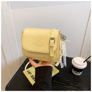 Détail du petit sac bandoulière en cuir froissé jaune clair avec breloque cœur