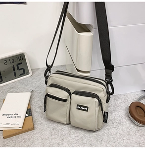 Detail shot of the multi-pocket canvas crossbody bag with branded woven labels