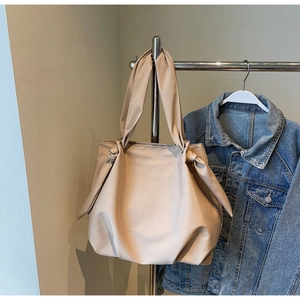 Detail of minimalist apricot tote bag with stylish knot strap hanging on hanger